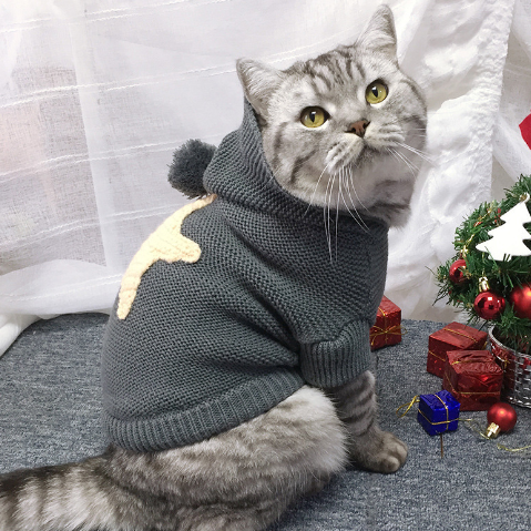 Star Knit Pet Sweater – cat wearing a gray hooded sweater with Christmas decorations in the background